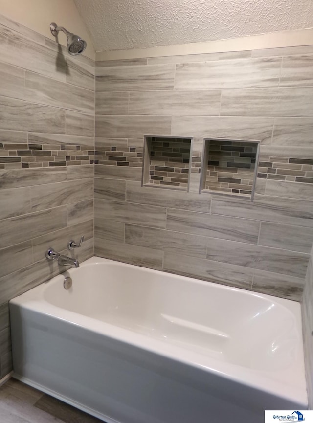 bathroom featuring wood-type flooring, a textured ceiling, and tiled shower / bath