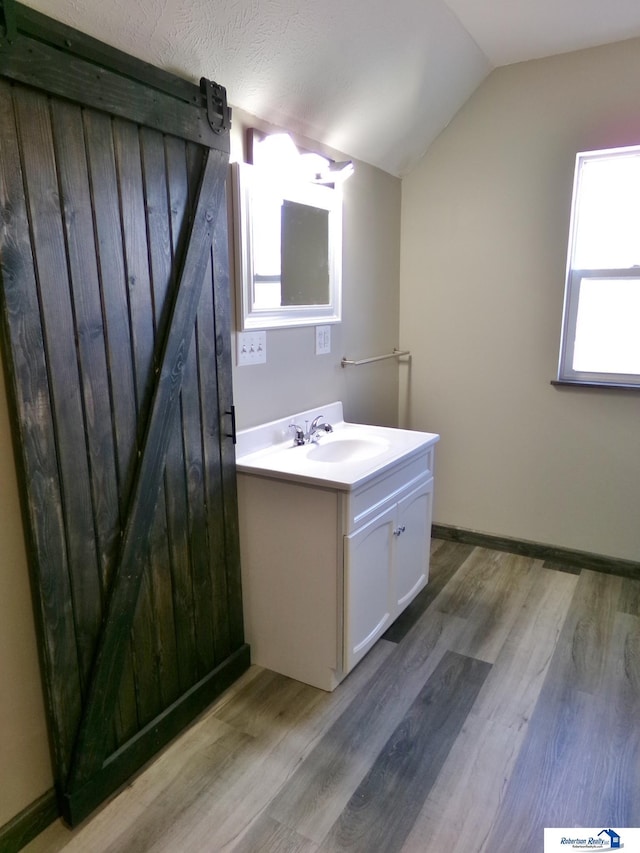 bathroom with vanity, wood-type flooring, lofted ceiling, and a textured ceiling