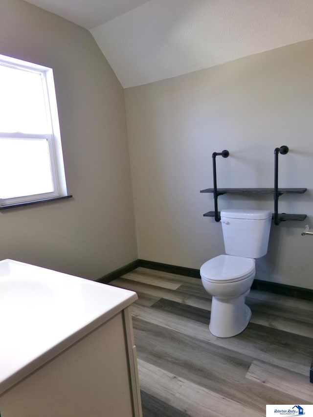 bathroom with vanity, wood-type flooring, vaulted ceiling, and toilet