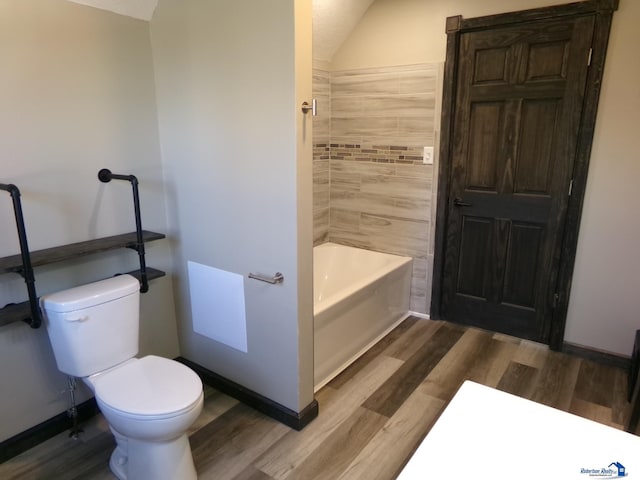 bathroom featuring hardwood / wood-style floors, vaulted ceiling, toilet, and shower / bathtub combination