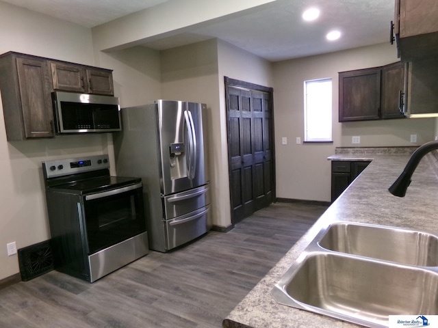 kitchen with hardwood / wood-style floors, sink, dark brown cabinetry, and stainless steel appliances