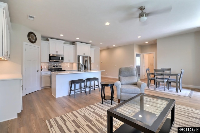 living room with ceiling fan and light hardwood / wood-style floors