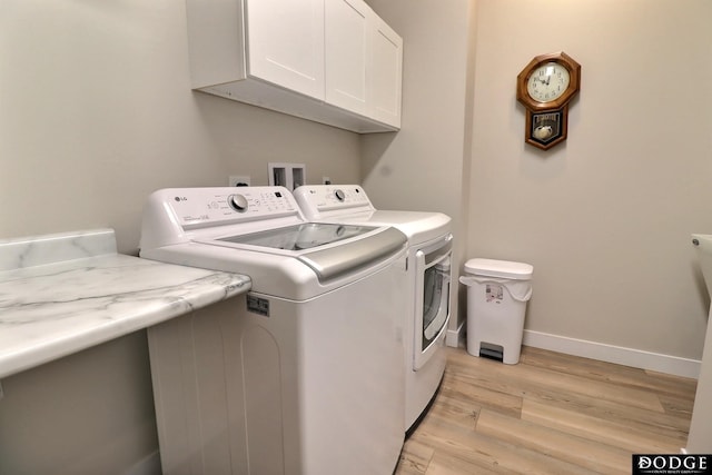 laundry area featuring cabinets, separate washer and dryer, and light hardwood / wood-style floors