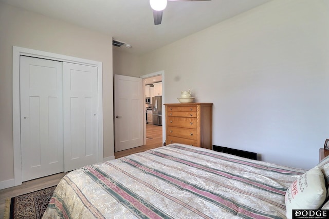 bedroom featuring ceiling fan, stainless steel fridge with ice dispenser, light hardwood / wood-style flooring, and a closet