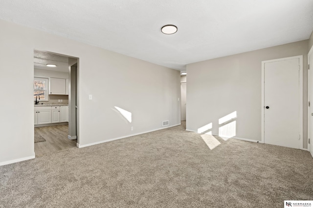 empty room with light colored carpet and sink