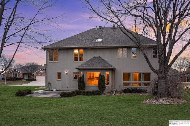 back house at dusk with a yard, a patio area, and a garage