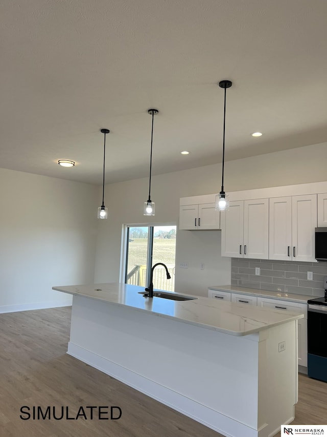 kitchen featuring an island with sink, pendant lighting, decorative backsplash, sink, and electric range oven