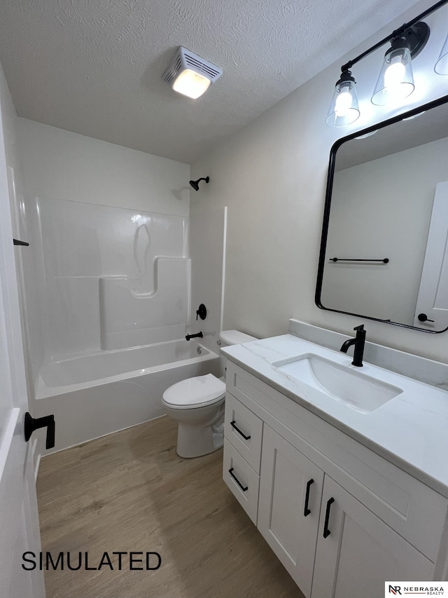 full bathroom featuring toilet, a textured ceiling, tub / shower combination, wood-type flooring, and vanity