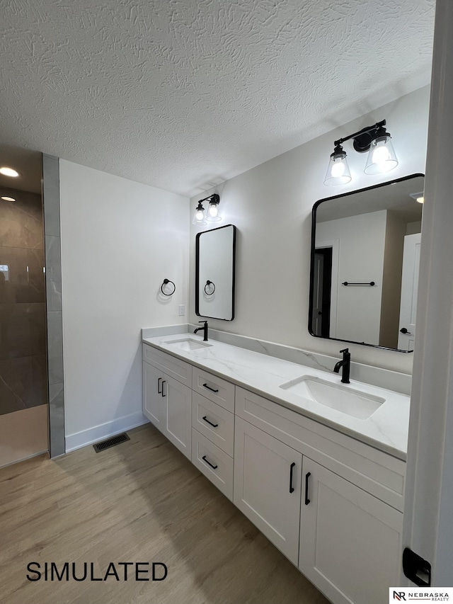 bathroom with a textured ceiling, a shower, vanity, and hardwood / wood-style flooring