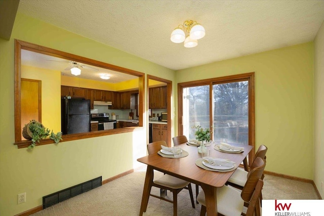 dining area featuring ceiling fan with notable chandelier, light colored carpet, and a textured ceiling