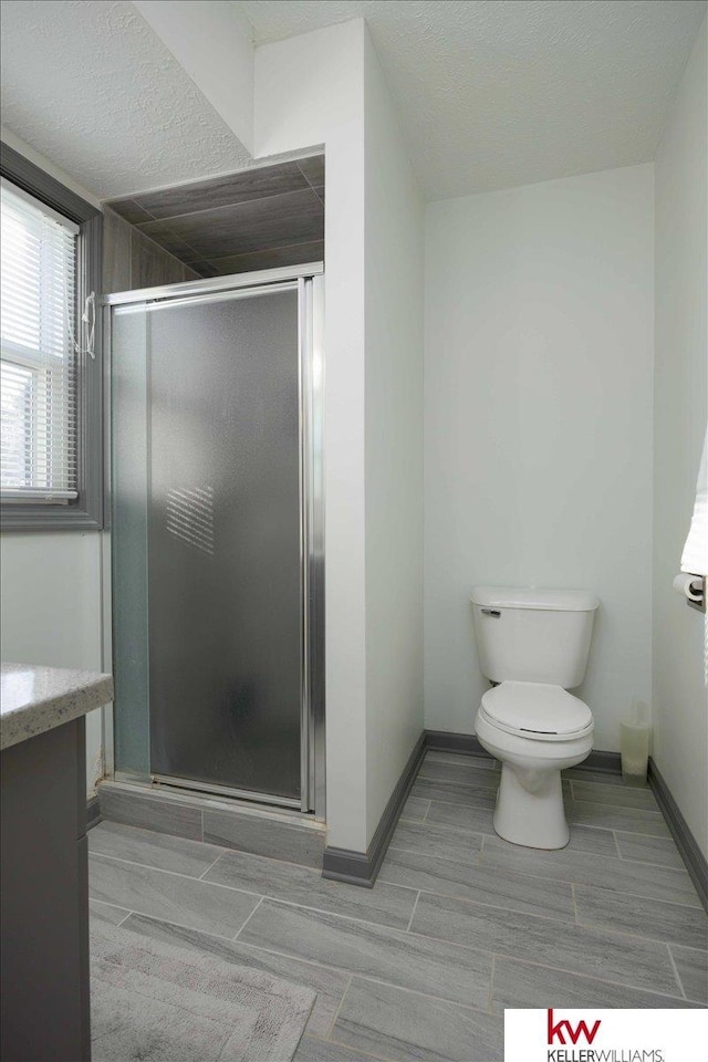 bathroom with toilet, vanity, and a shower with door