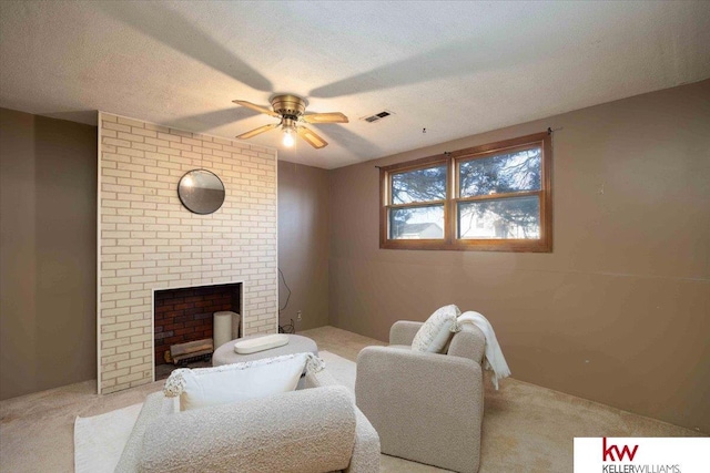 living room with a textured ceiling, ceiling fan, light carpet, and a brick fireplace