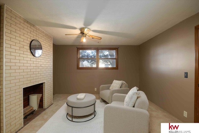 living room with ceiling fan, light colored carpet, a brick fireplace, and a textured ceiling