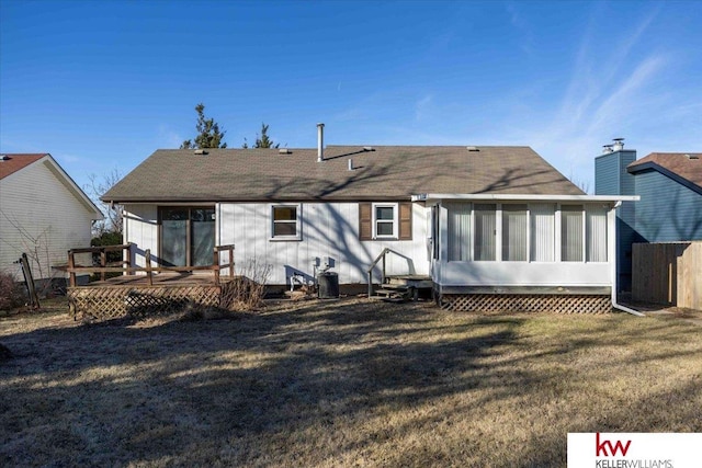 back of property with a wooden deck, central air condition unit, a sunroom, and a lawn