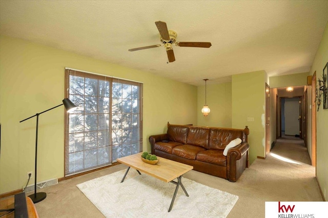 living room featuring a textured ceiling, ceiling fan, and light colored carpet