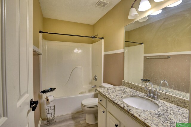 full bathroom featuring toilet, a textured ceiling, shower / bathtub combination, wood-type flooring, and vanity