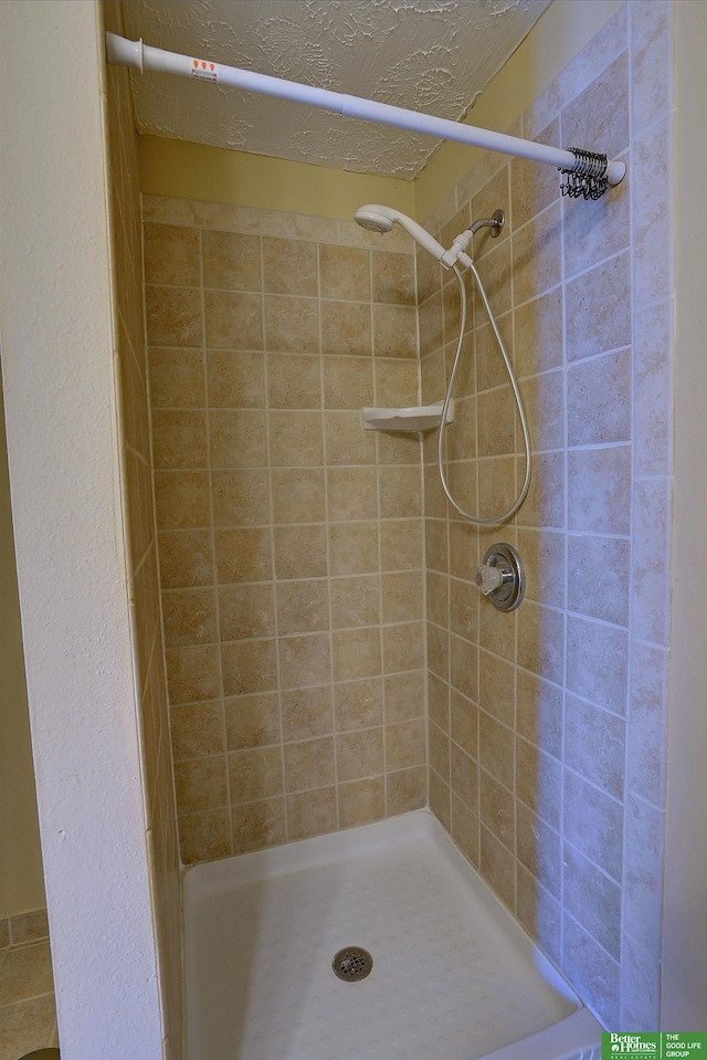 bathroom featuring a textured ceiling and tiled shower