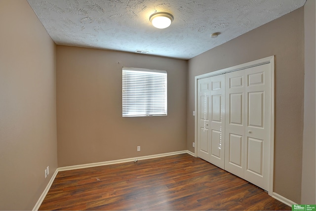 unfurnished bedroom featuring a closet, a textured ceiling, and dark hardwood / wood-style floors