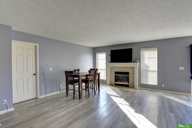 dining area featuring a premium fireplace, a textured ceiling, and light hardwood / wood-style floors