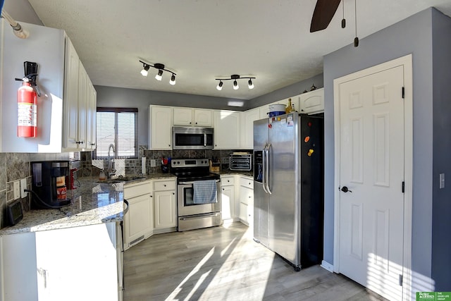 kitchen featuring light hardwood / wood-style flooring, tasteful backsplash, white cabinetry, appliances with stainless steel finishes, and sink