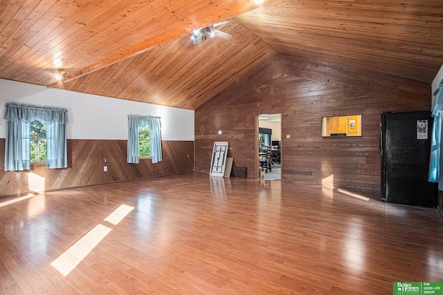 unfurnished living room with lofted ceiling, wood walls, a wealth of natural light, and wood ceiling