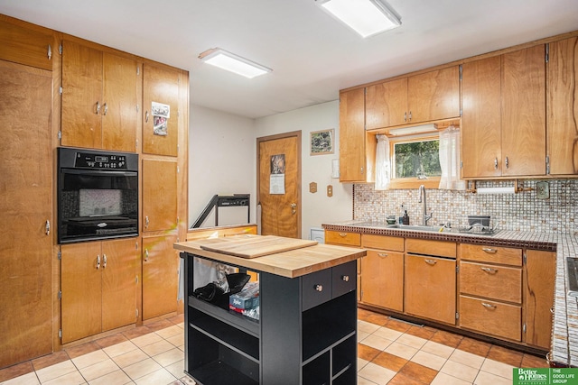 kitchen with sink, light tile patterned flooring, tasteful backsplash, and oven