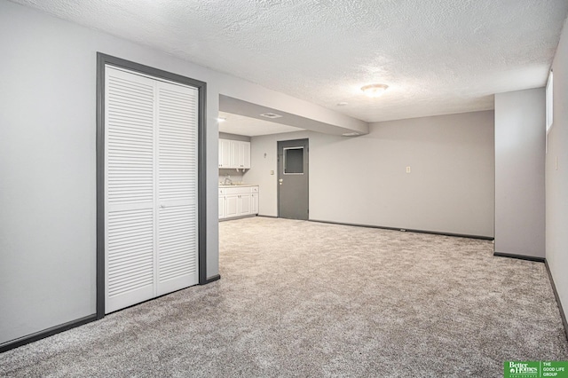 basement with light colored carpet, a textured ceiling, and sink