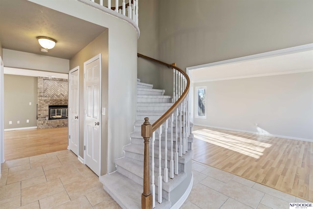 stairs with a brick fireplace and tile patterned floors