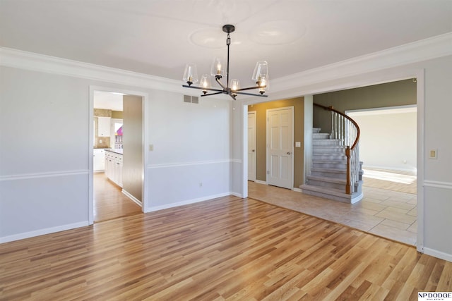 empty room featuring crown molding, a notable chandelier, and light hardwood / wood-style flooring