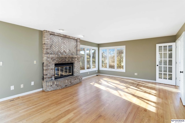 unfurnished living room with a brick fireplace and light wood-type flooring