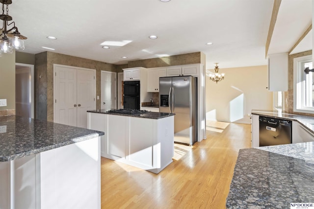 kitchen featuring a chandelier, decorative light fixtures, black appliances, light wood-type flooring, and white cabinets