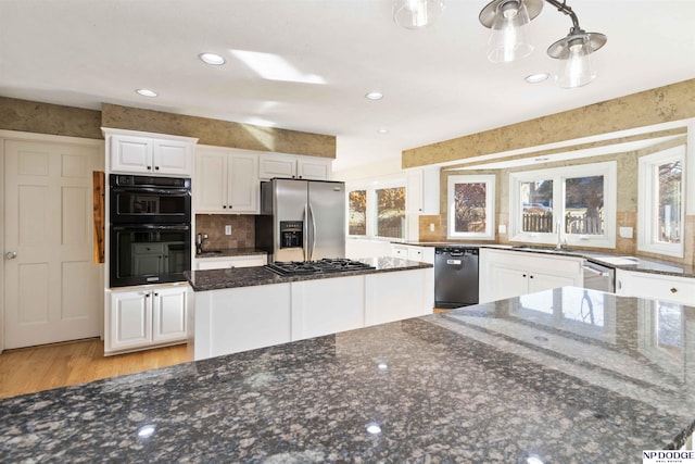 kitchen with sink, white cabinets, a center island, dark stone counters, and black appliances