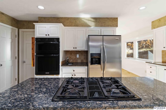 kitchen with decorative backsplash, white cabinetry, dark stone countertops, and black appliances