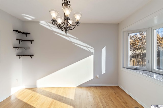 unfurnished dining area featuring light hardwood / wood-style floors, an inviting chandelier, and a wealth of natural light