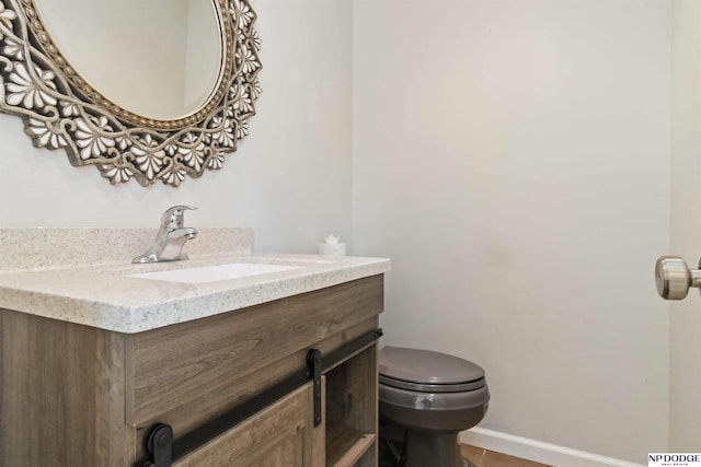 bathroom with toilet, vanity, and tile patterned flooring