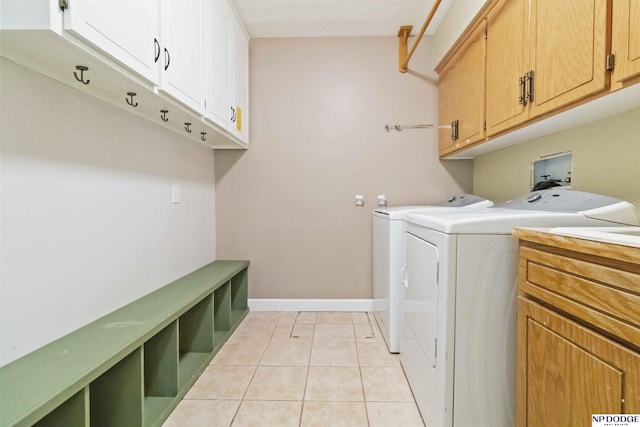 clothes washing area with cabinets, light tile patterned flooring, and independent washer and dryer