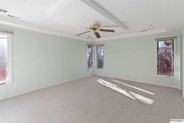 unfurnished room with ceiling fan, light carpet, and a tray ceiling