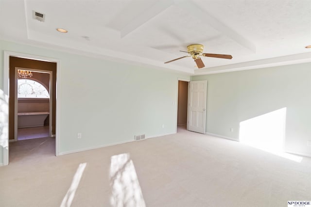 unfurnished room with a raised ceiling, light colored carpet, and ceiling fan