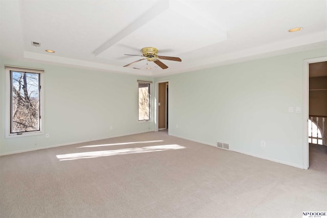 carpeted spare room featuring a raised ceiling and ceiling fan