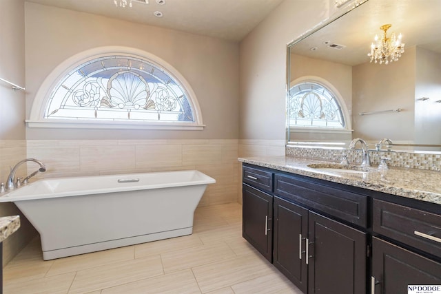 bathroom featuring tile patterned flooring, a notable chandelier, a bathtub, and vanity