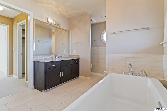 bathroom with toilet, vanity, and a bathtub