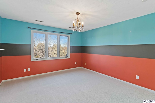 carpeted empty room featuring a chandelier