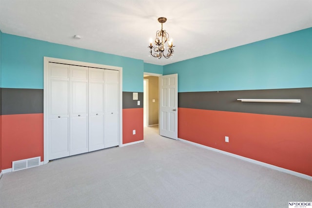 unfurnished bedroom with light colored carpet, a closet, and a chandelier