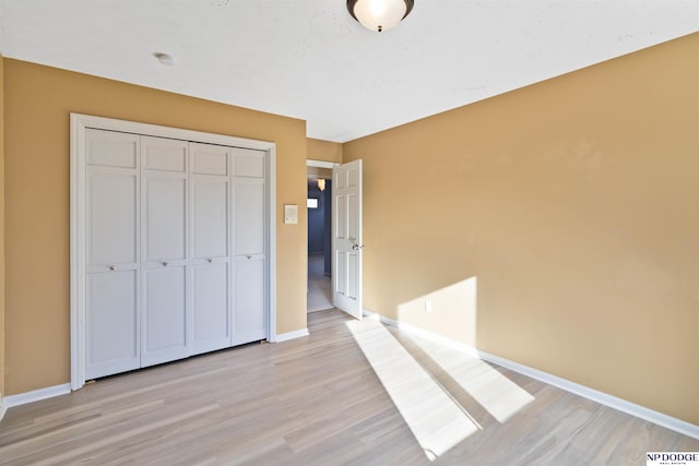 unfurnished bedroom with a closet and light hardwood / wood-style flooring