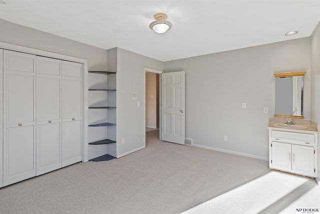 unfurnished bedroom featuring sink, light colored carpet, and a closet