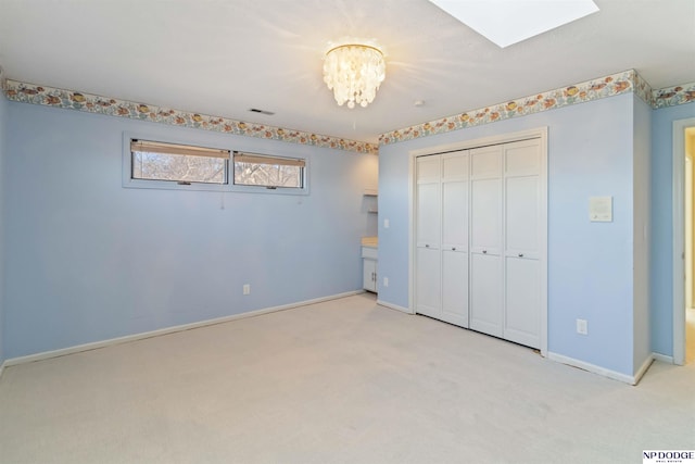 unfurnished bedroom featuring light colored carpet, an inviting chandelier, and a closet