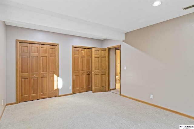 unfurnished bedroom featuring two closets and carpet flooring