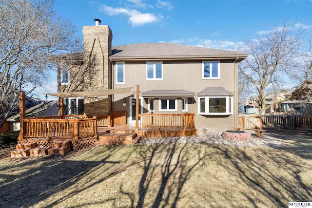 rear view of house with a yard, a fire pit, and a wooden deck