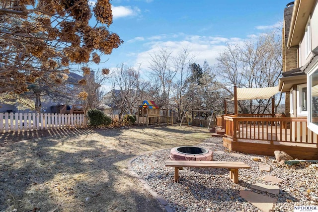 view of yard with a deck, an outdoor fire pit, and a playground