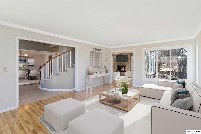 living room with hardwood / wood-style flooring, a chandelier, ornamental molding, and a fireplace